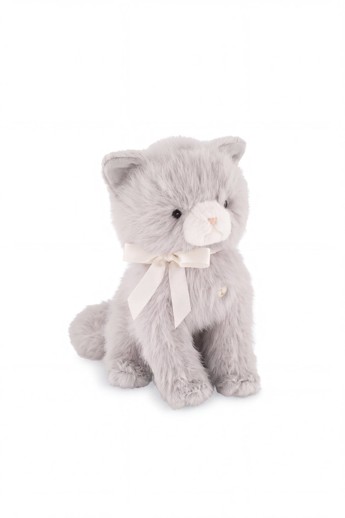 A soft grey plush kitten toy sitting upright, featuring a cream-colored muzzle with delicate embroidered facial details and a white satin ribbon bow tied around its neck.