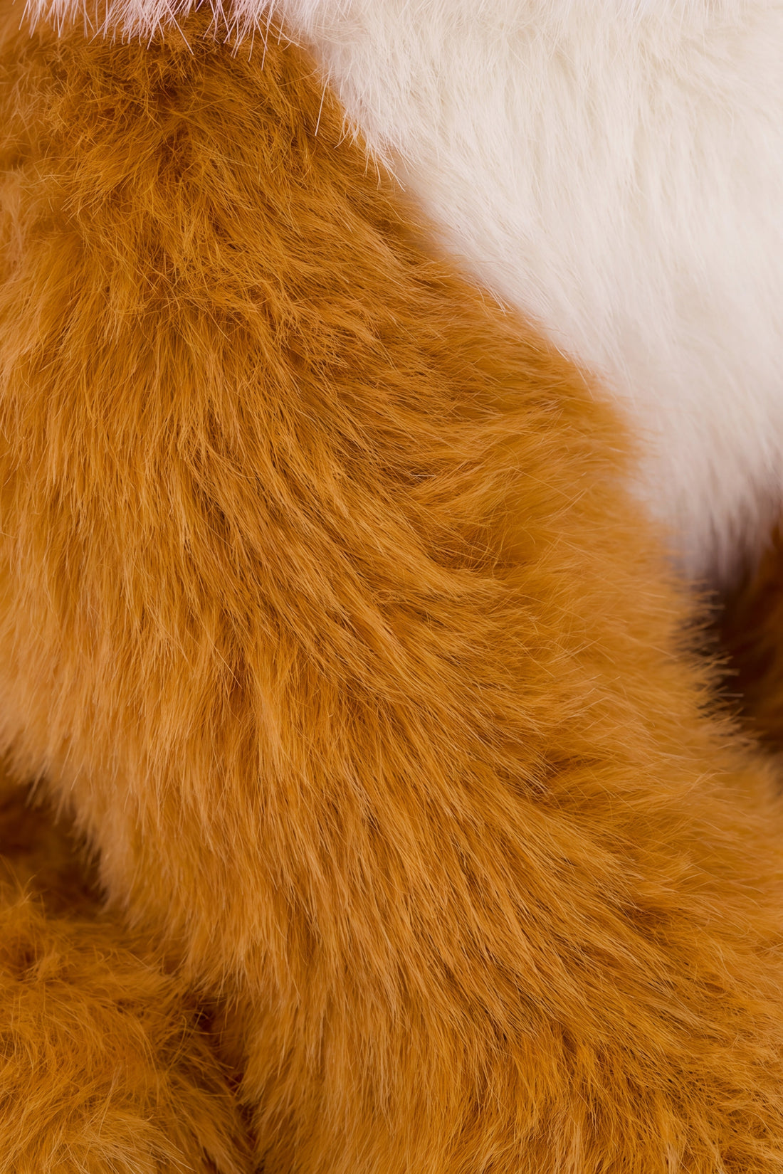 A close-up view of the soft, textured, rust-colored fur on the arm and shoulder of Archie the Fox plush toy.
