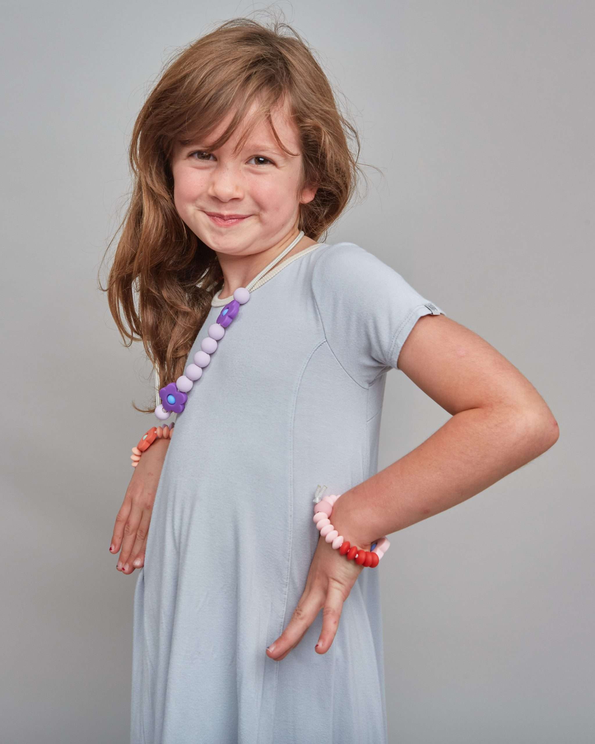 Young girl wearing colorful bracelets on a plain background
