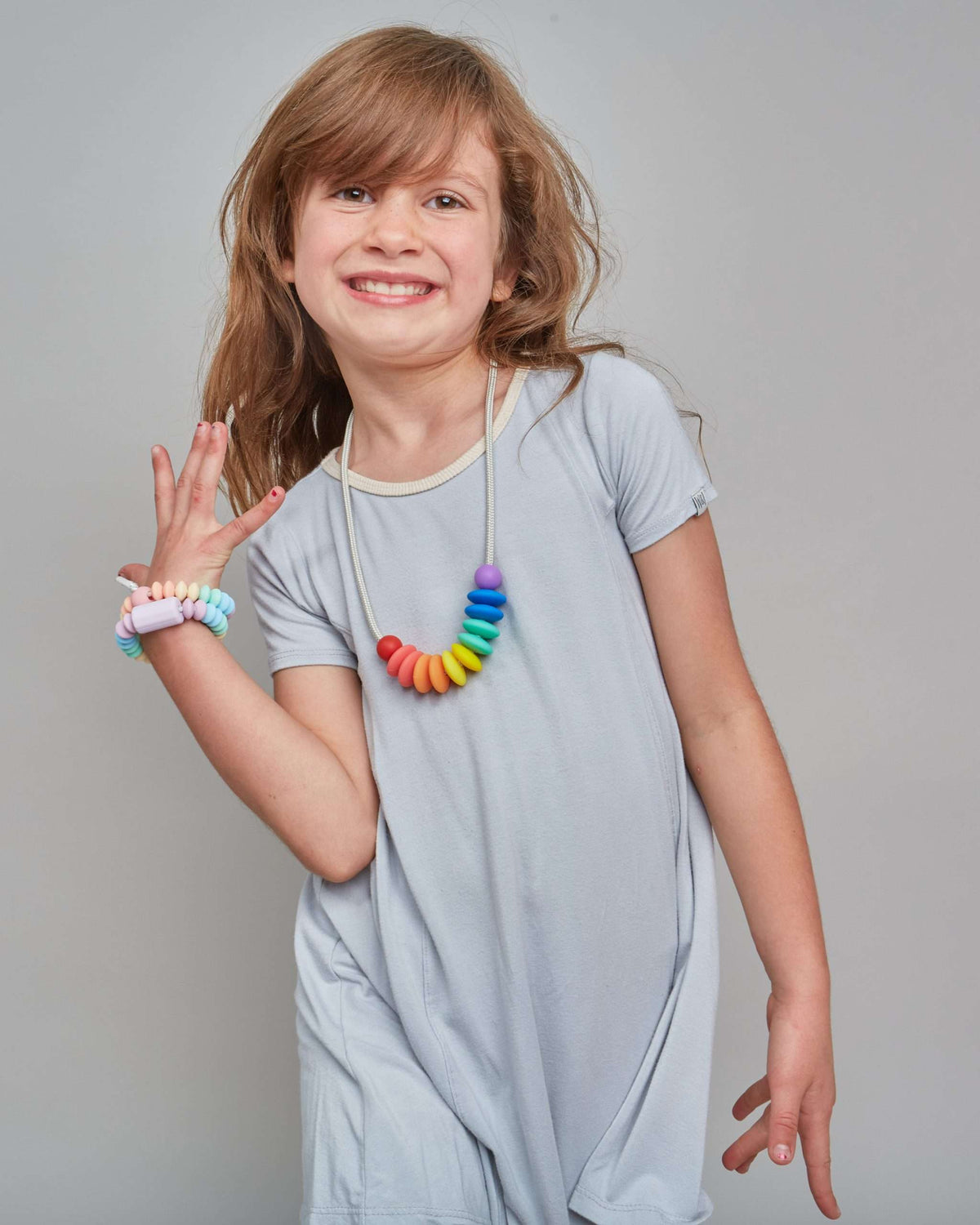 Child wearing a colorful necklace and bracelets on a plain background