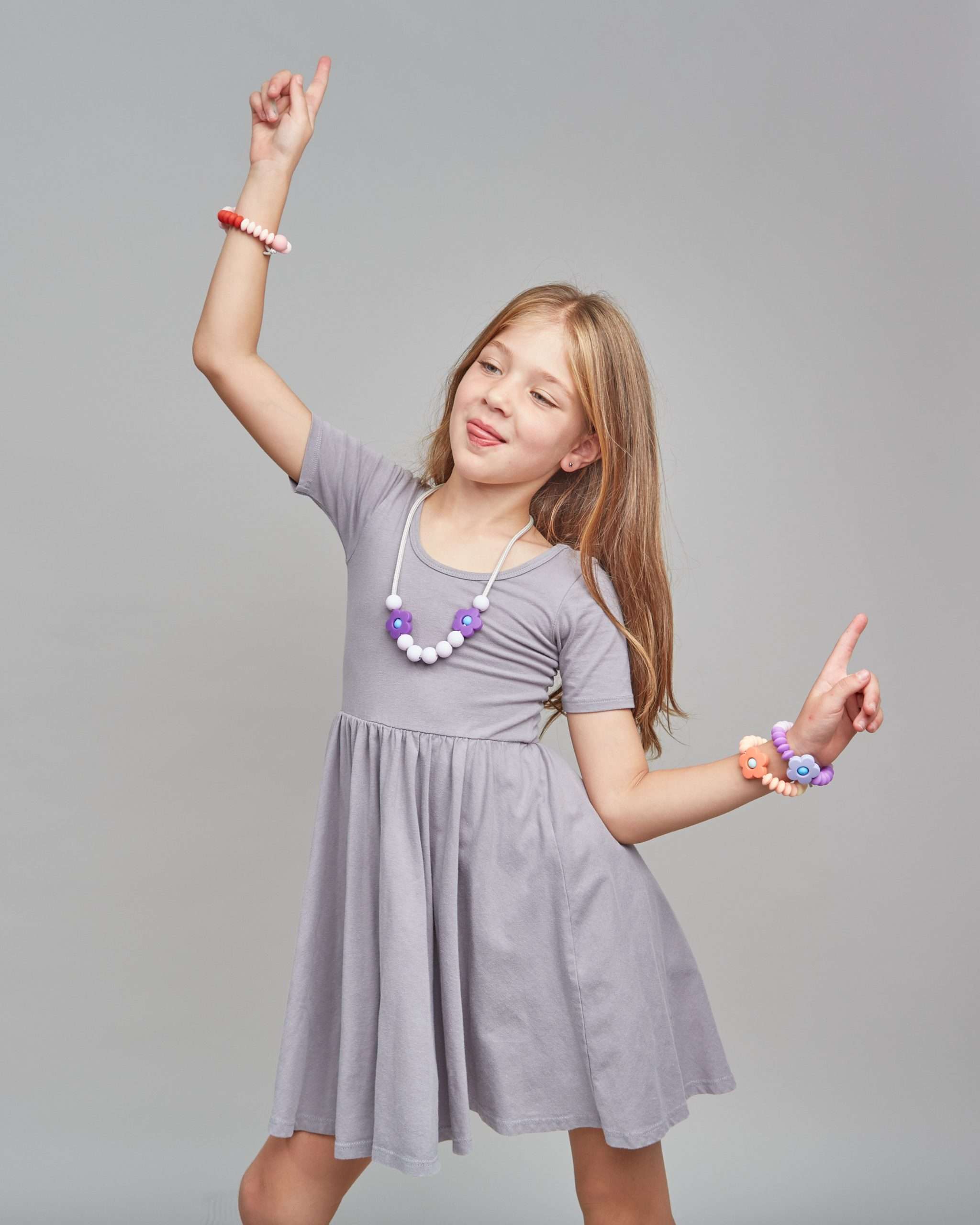 Young girl in a gray dress with jewelry on a gray background