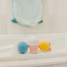 Three colorful bath toys on a white surface with a blurred background