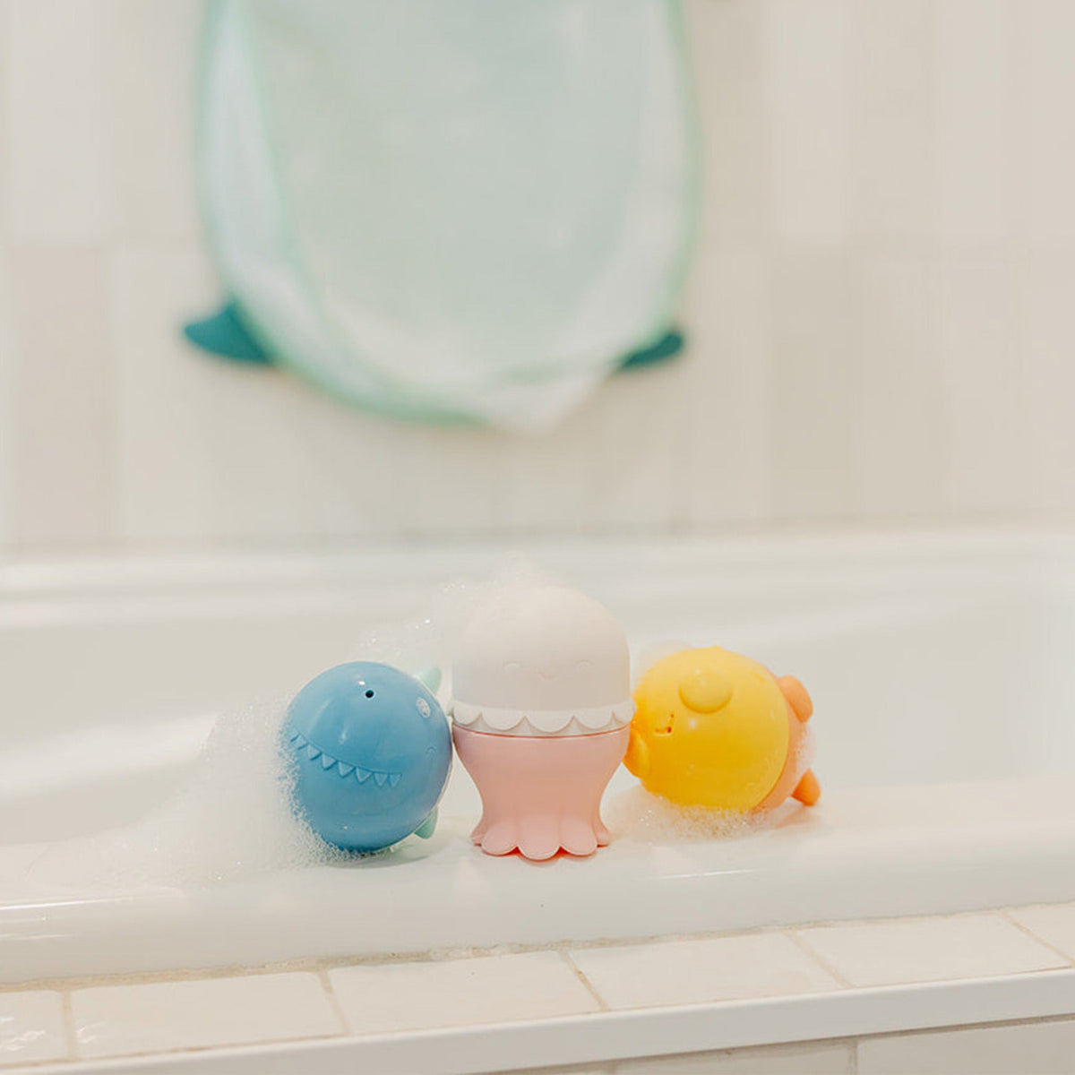 Three colorful bath toys on a white surface with a blurred background
