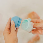 Person holding two blue silicone cups with a neutral background