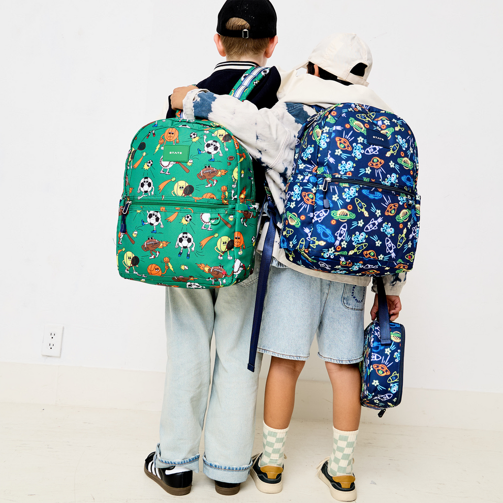 Two children wearing colorful backpacks with cartoon designs on a white background