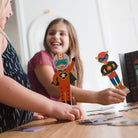 Two children playing with superhero figurines at a table.