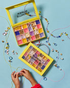 Colorful beading kit with open box and strings of beads on a blue background