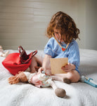 Child reading a book with toys on a bed