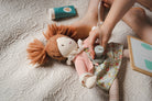 Child playing with a doll and stethoscope on a bed