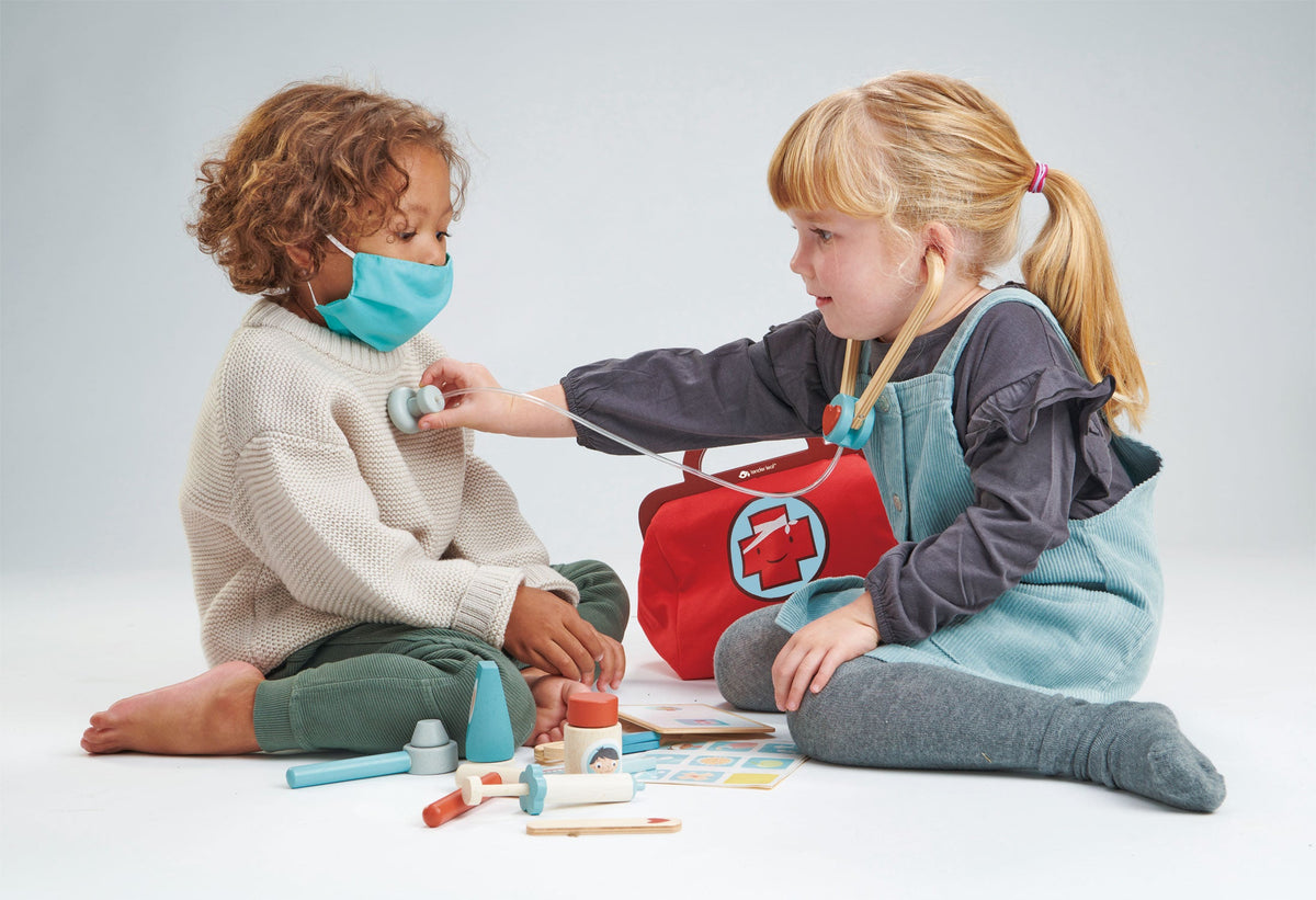 Two children playing with medical toys on a light gray background