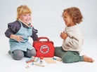 Two children playing with a toy doctor set on a white background