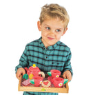 Child holding a wooden tea set with a white background