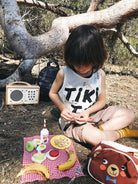 Child sitting on the ground with a picnic setup in a natural setting