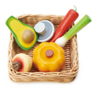 Toy fruits and vegetables in a woven basket on a white background