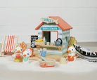 Toy fish and chip shop with toy ducks and a small chair on a white surface.