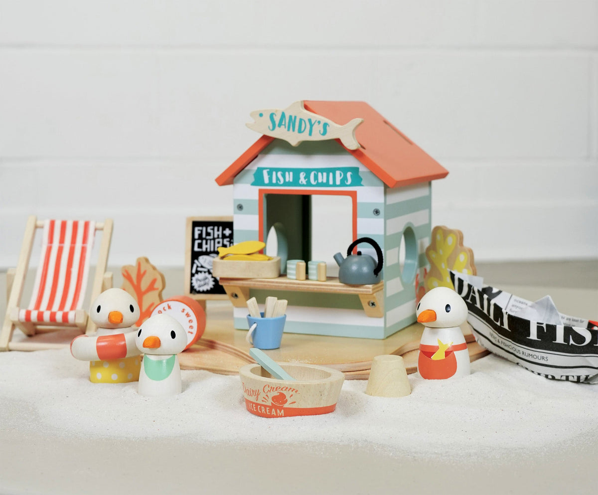 Toy fish and chip shop with toy ducks and a small chair on a white surface.