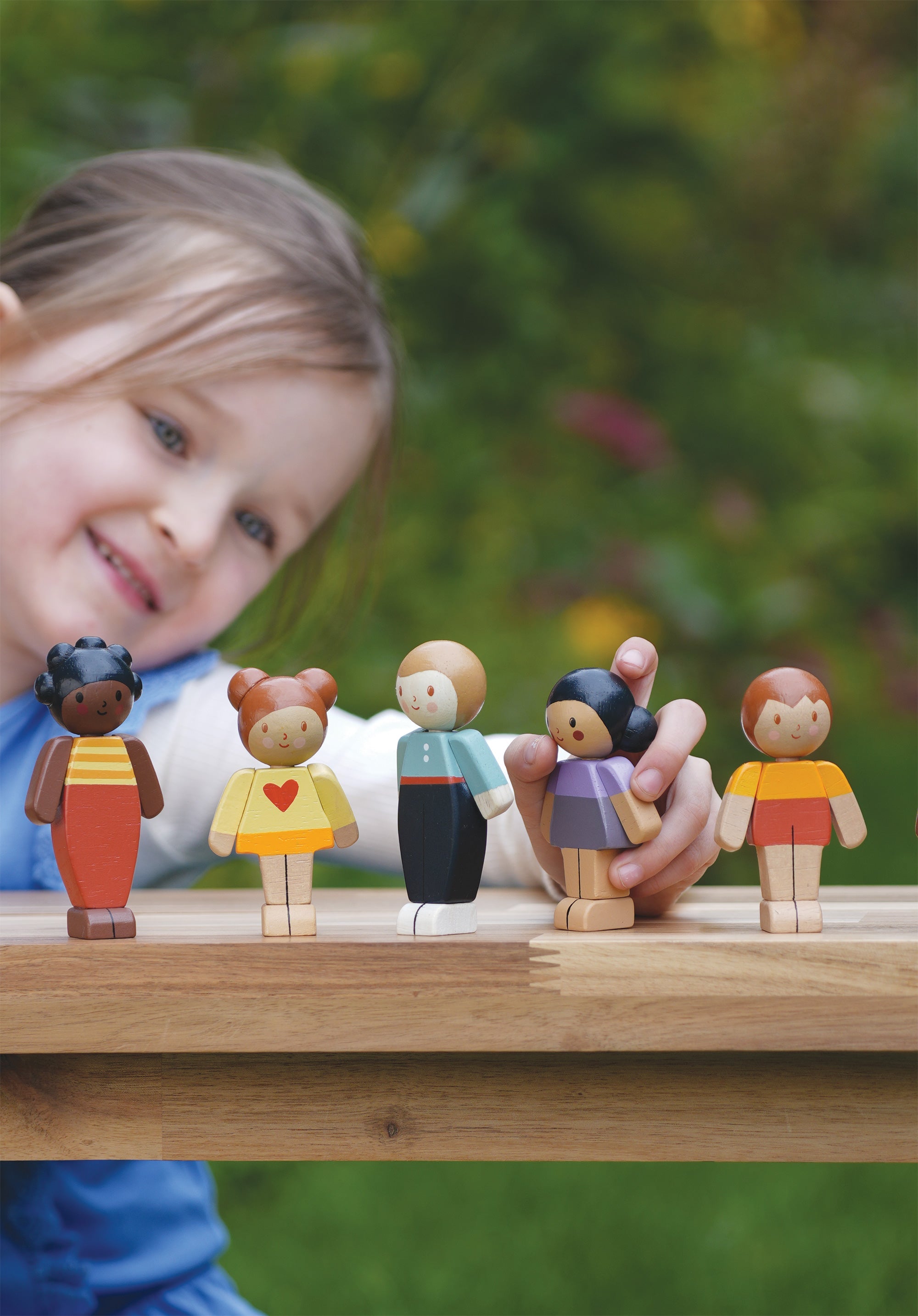 Child playing with wooden toy figures outdoors
