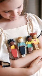 Child holding a set of diverse wooden toy figures