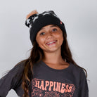 Person wearing a black beanie with white patterns and a dark gray sweatshirt with 'HAPPINESS' text.
