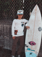 Person holding a surfboard with a chain-link fence in the background