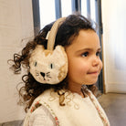 Child wearing a fluffy animal-themed earmuff indoors