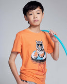 Child wearing an orange t-shirt with a tiger graphic, holding a blue hula hoop against a gray background