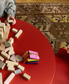 Colorful building blocks on a red table with a patterned rug in the background