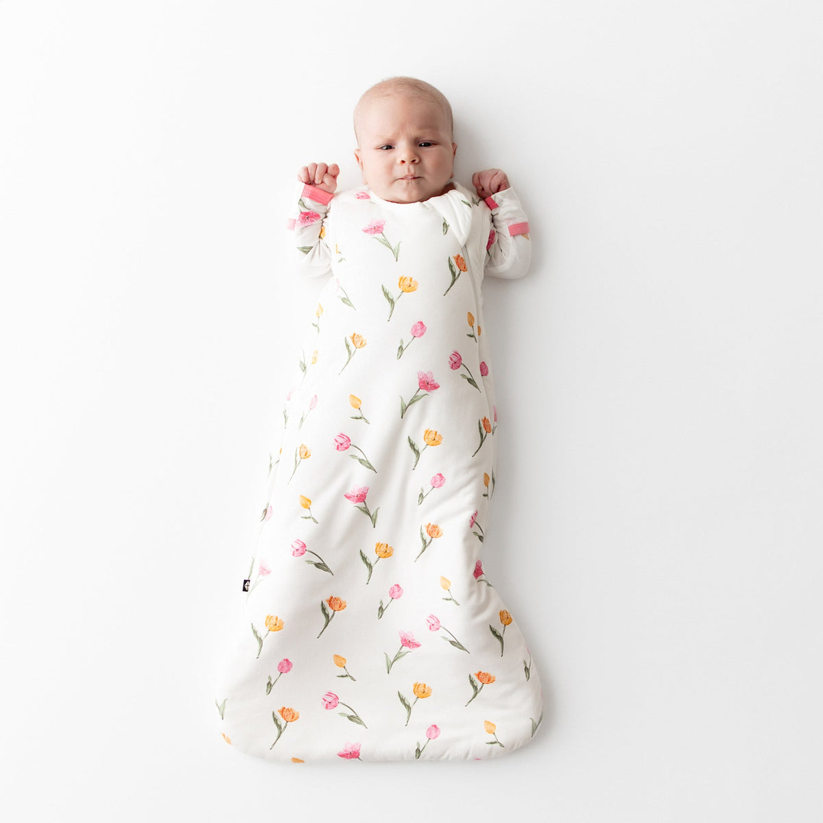 Baby wrapped in a floral-patterned swaddle on a white background