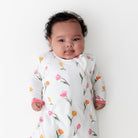 Baby wearing a white onesie with floral patterns on a white background