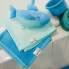 Set of blue and green towels with a shark-shaped towel on a white surface