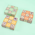 Three colorful children's blocks with alphabet and animal illustrations on a light green background