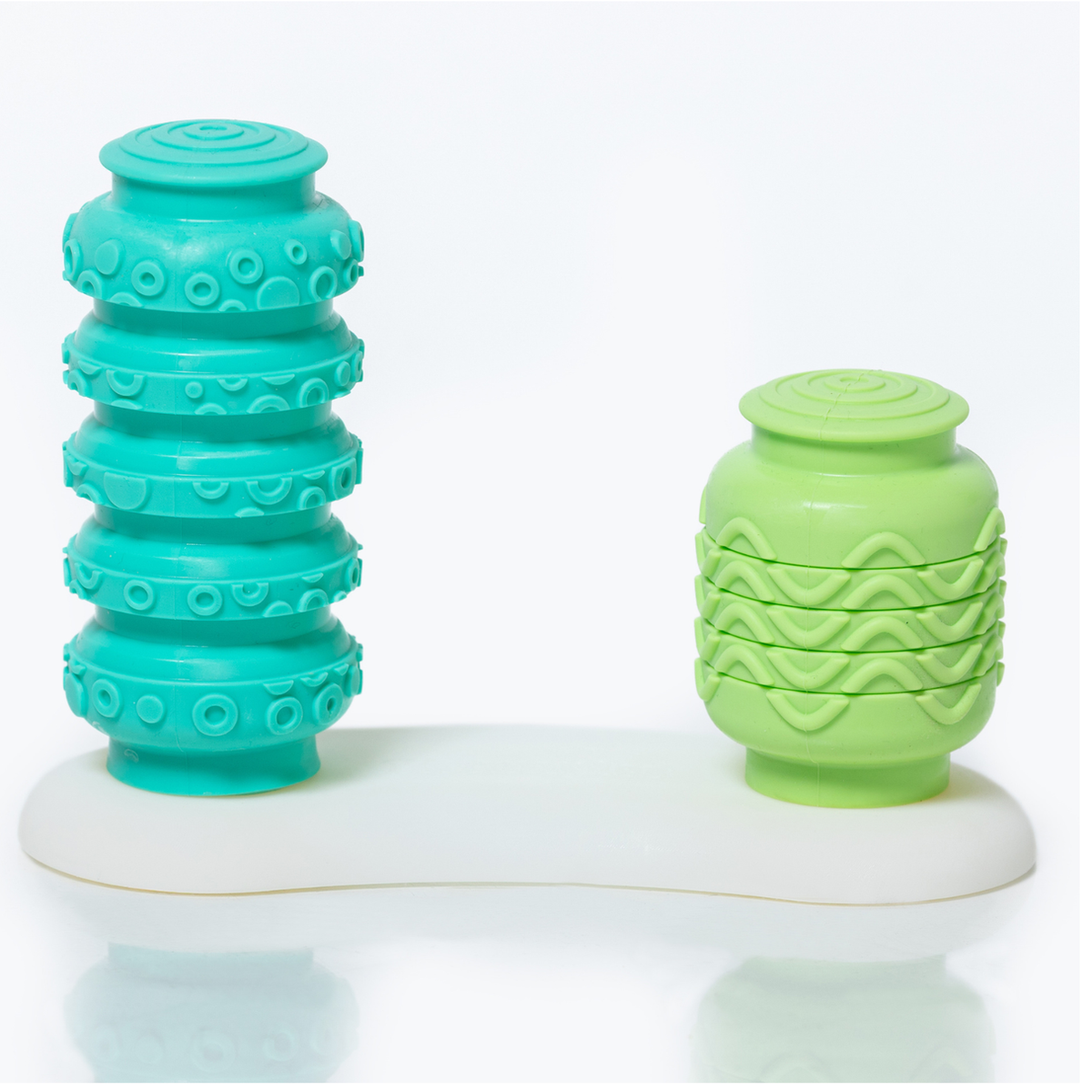 Two green textured objects on a white platform with a white background