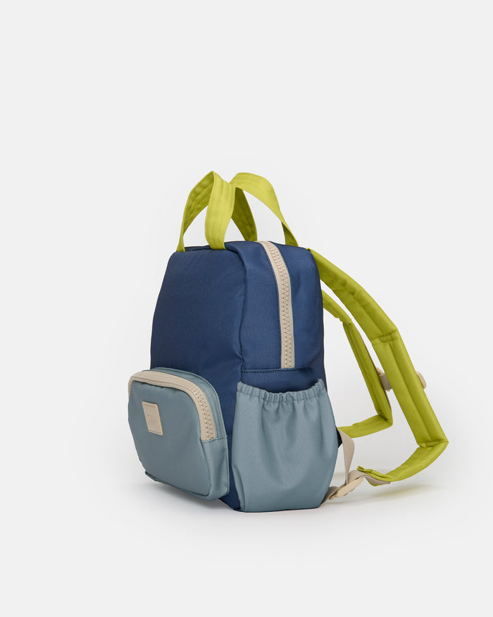 A small color-blocked backpack in navy blue, light blue, and lime green, shown from a three-quarter angle on a light gray background.
