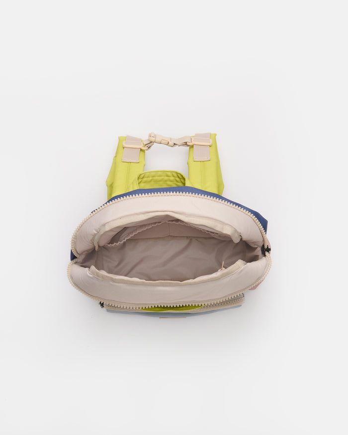A lime green backpack shown from a top-down view with its main compartment open, revealing a beige interior lining and a blue zipper trim.