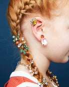 Close-up of a person wearing colorful earrings with a blue background