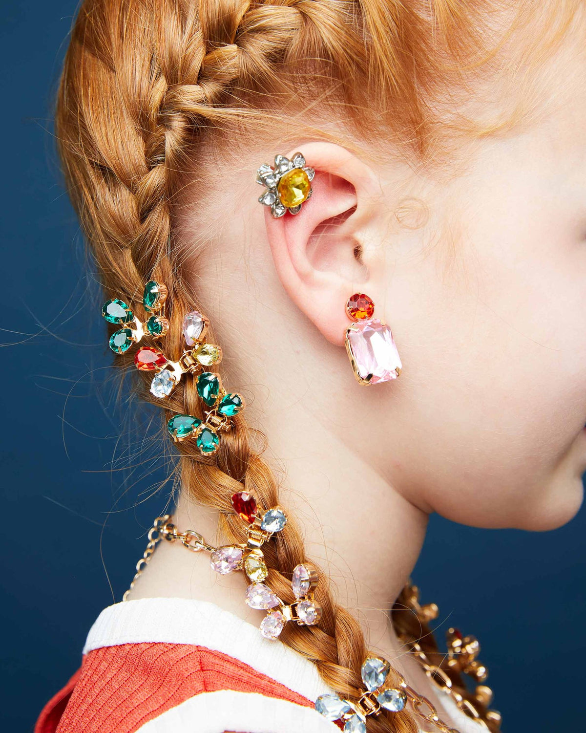 Close-up of a person wearing colorful earrings with a blue background