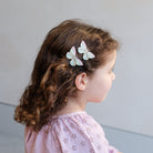 Child with butterfly hair clips on a plain background