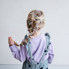 Child with braided hair featuring colorful hair clips on a plain background