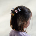 Person wearing colorful star-shaped hair clips on a plain background
