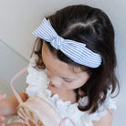 A girl wearing striped headband with a bow on a grey background