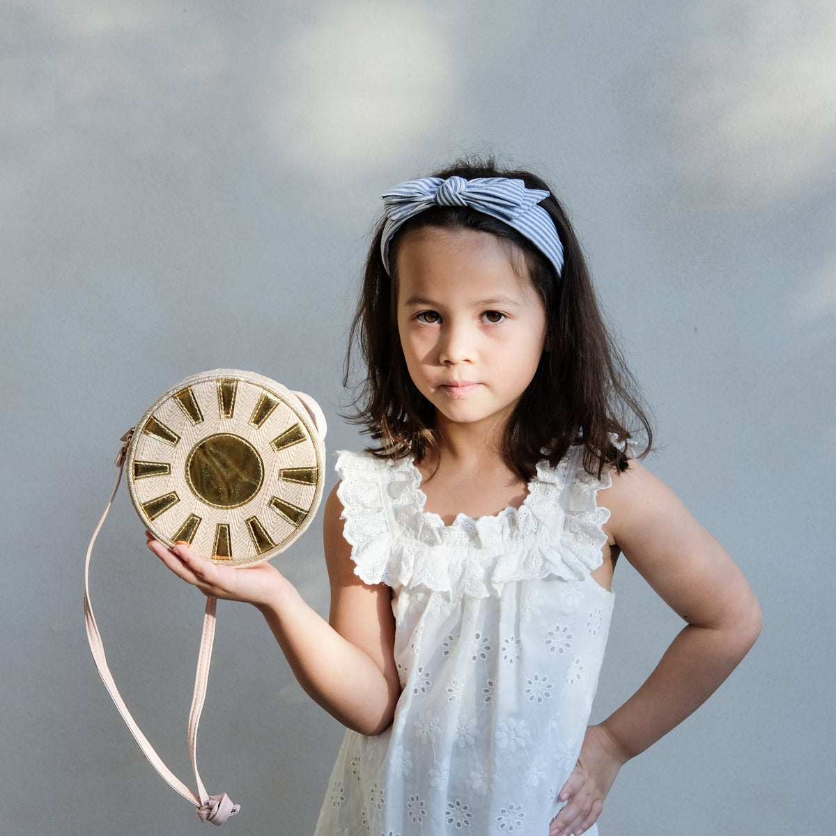 Young girl holding a decorative bag against a plain background