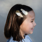 Young girl with decorative hair clips on a plain background