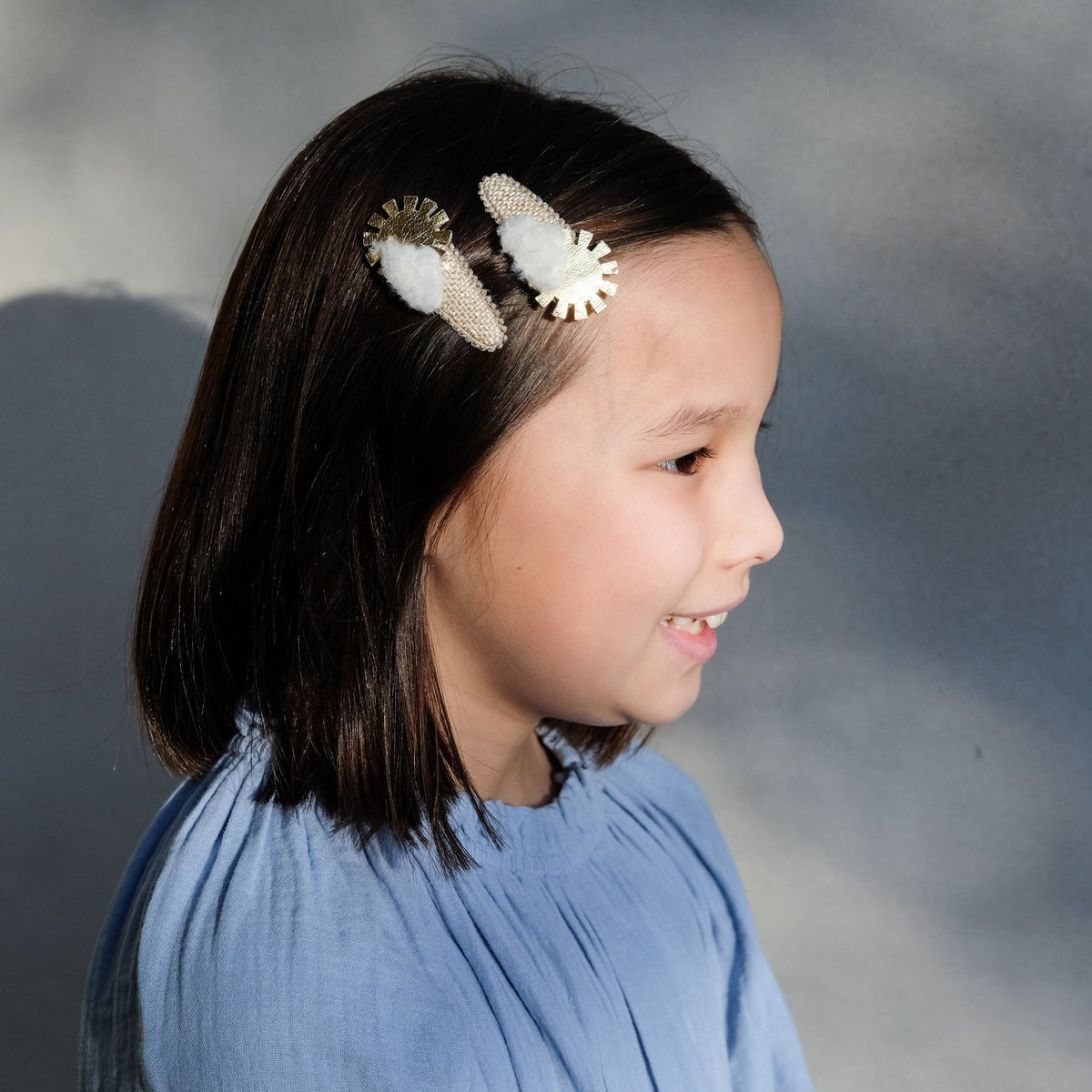 Young girl with decorative hair clips on a plain background