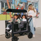 Woman pushing a stroller with children in front of a colorful mural.