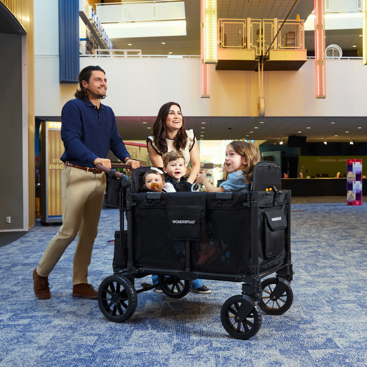 Family with children in a black wagon in a mall setting