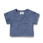 A dusty blue short-sleeve baby t-shirt with a textured terry cloth fabric, featuring a small chest pocket and a white brand label inside the collar, shown on a plain white background.