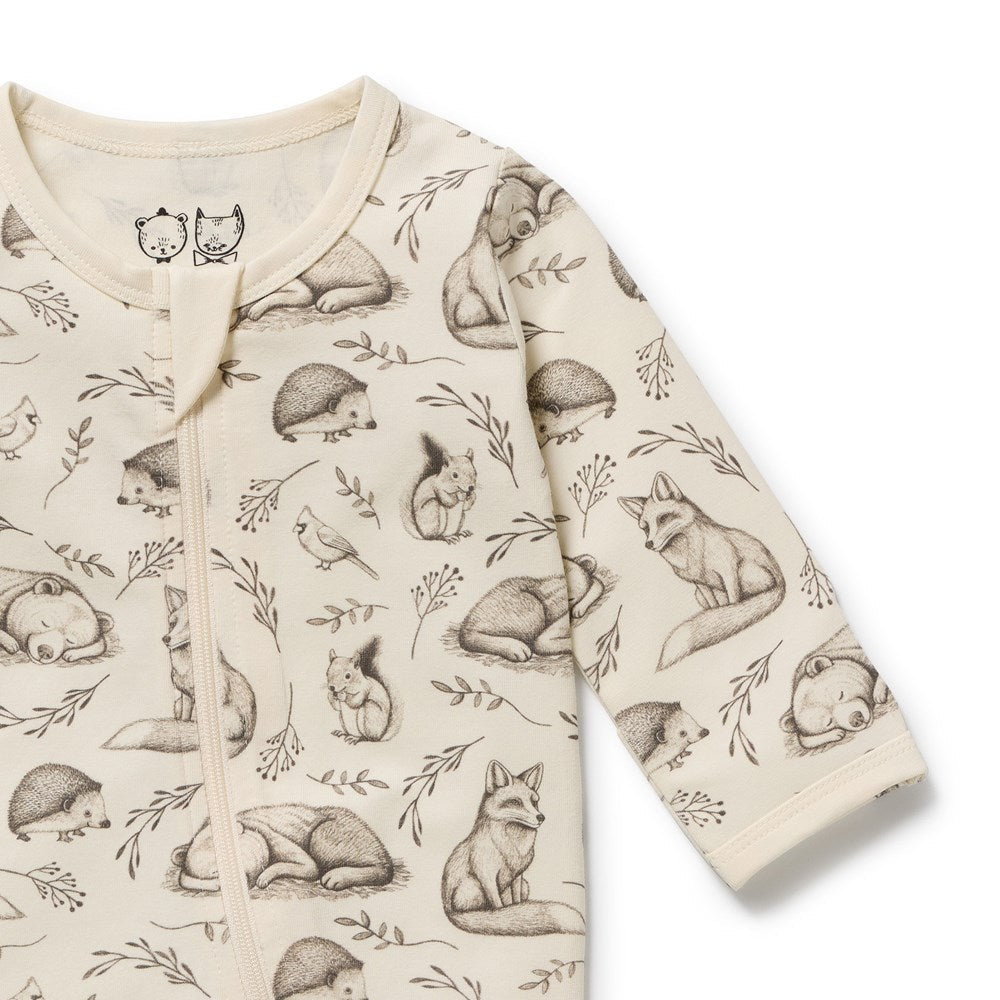 A long-sleeve baby romper in cream with a detailed print of woodland animals including foxes, hedgehogs, a squirrel, a bird, and leaves, shown on a plain white background.