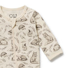 A long-sleeve baby romper in cream with a detailed print of woodland animals including foxes, hedgehogs, a squirrel, a bird, and leaves, shown on a plain white background.