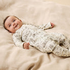 Baby wearing a patterned onesie lying on a beige surface