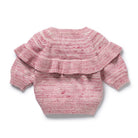Pink knitted baby sweater with ruffled details on a white background